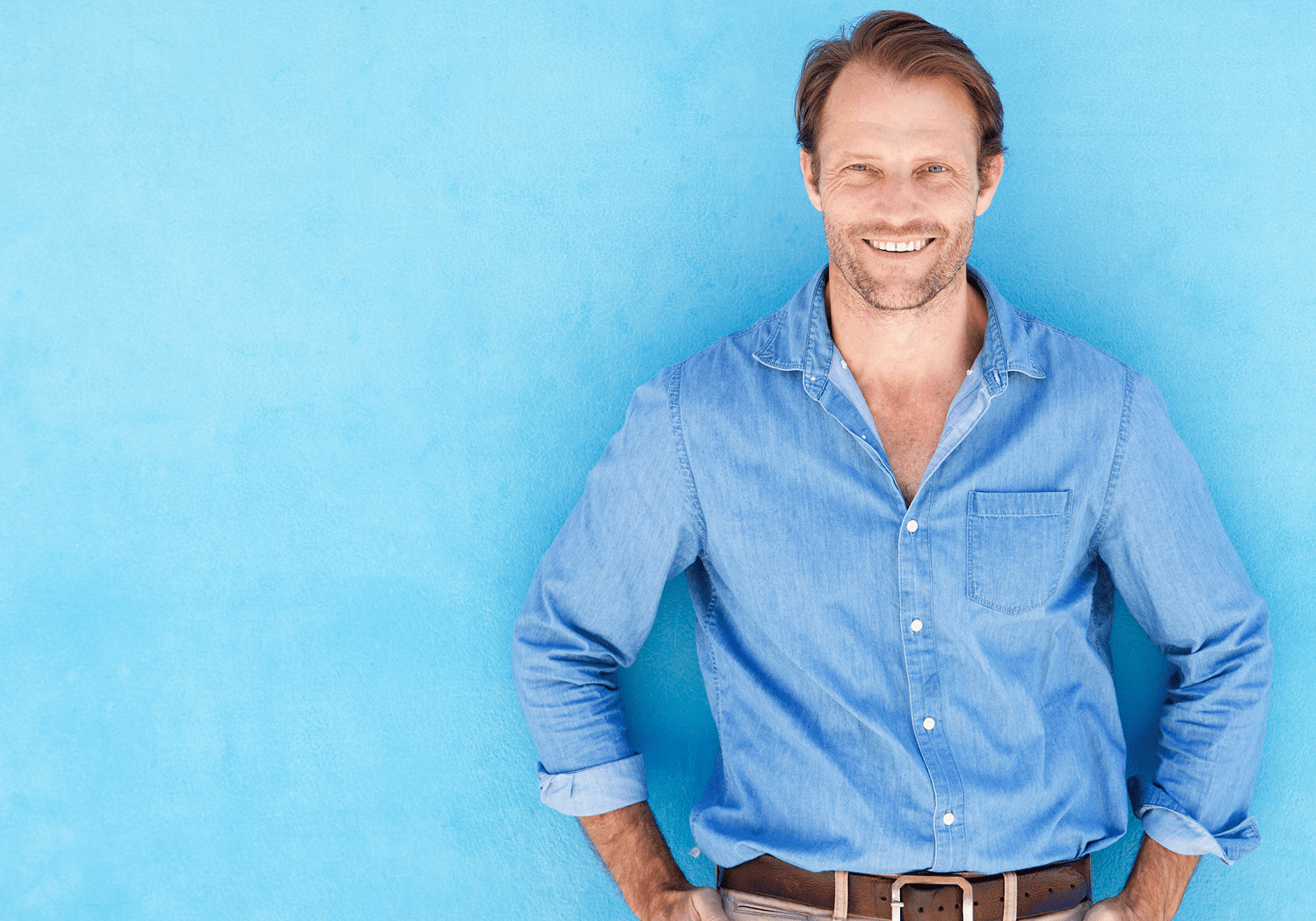 Smiling man in blue shirt against blue wall