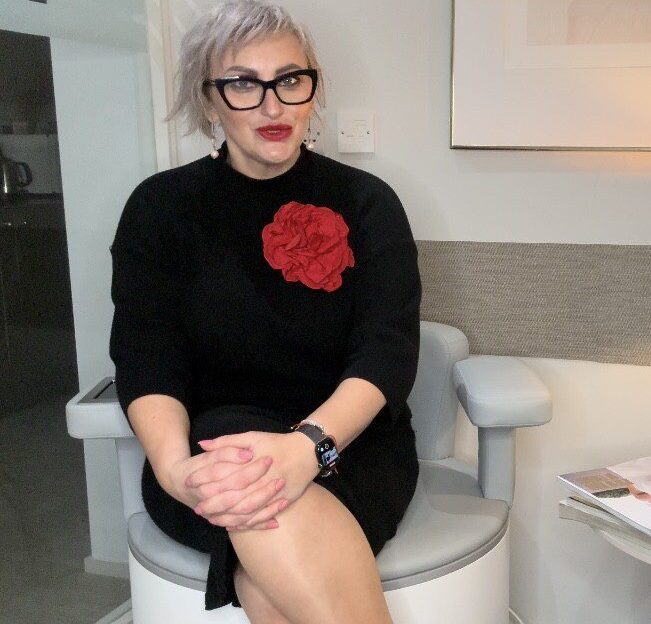 Seated person wearing black dress with red flower