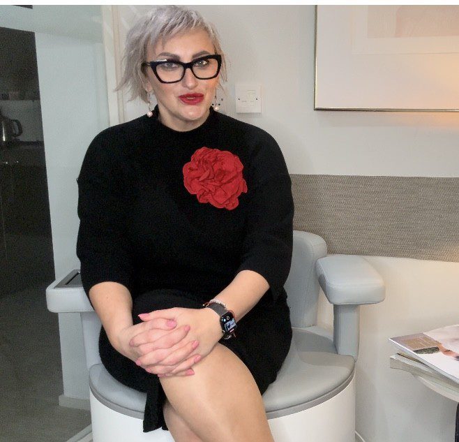 Seated person wearing black dress with red flower